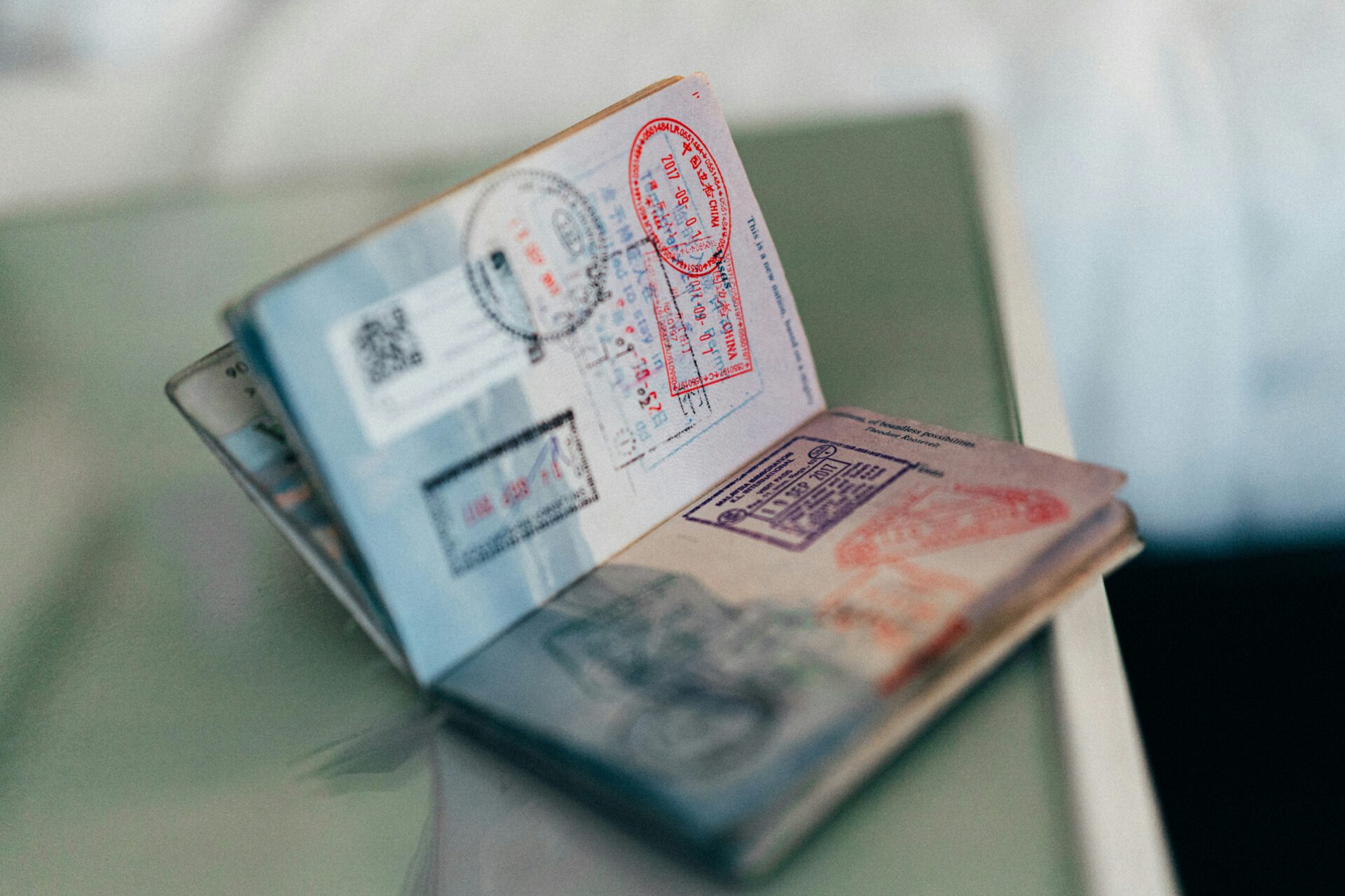 Ein geöffneter Reisepass liegt auf einer Fläche, auf der bunte Reisestempel und eine elektronische Reisegenehmigung zu sehen sind, die auf internationale Reisen und Grenzübertritte hinweisen.